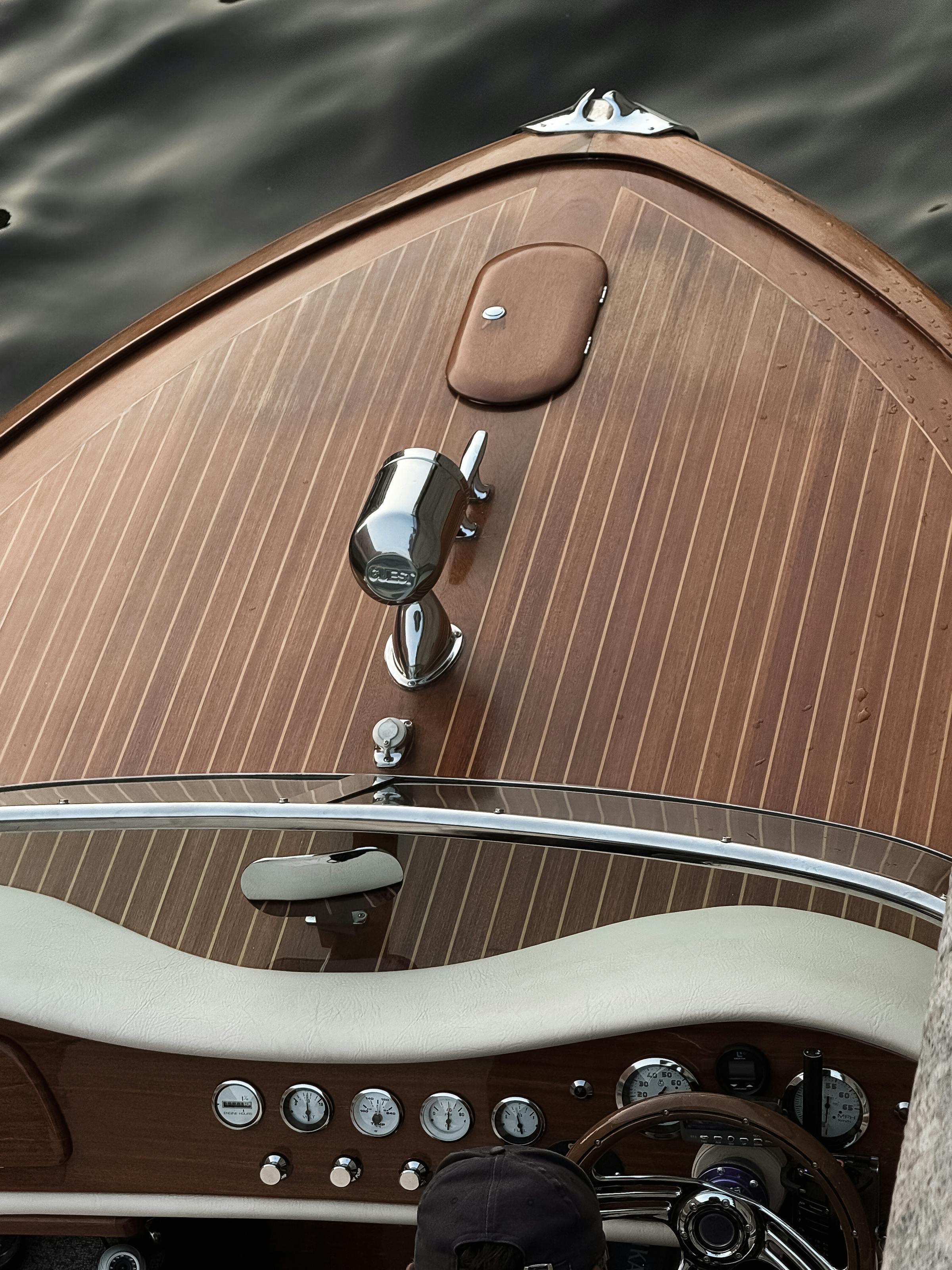 Top-down view of a polished mahogany deck with chrome bow chock and brass instruments.