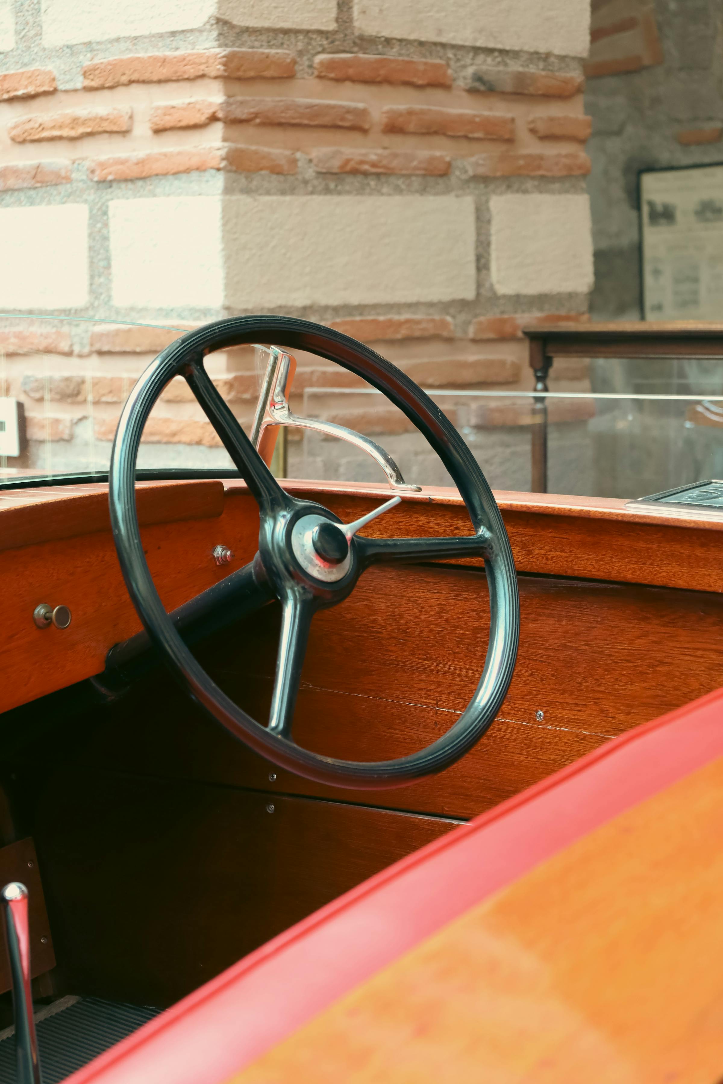 A vintage steering wheel on a varnished mahogany helm.
