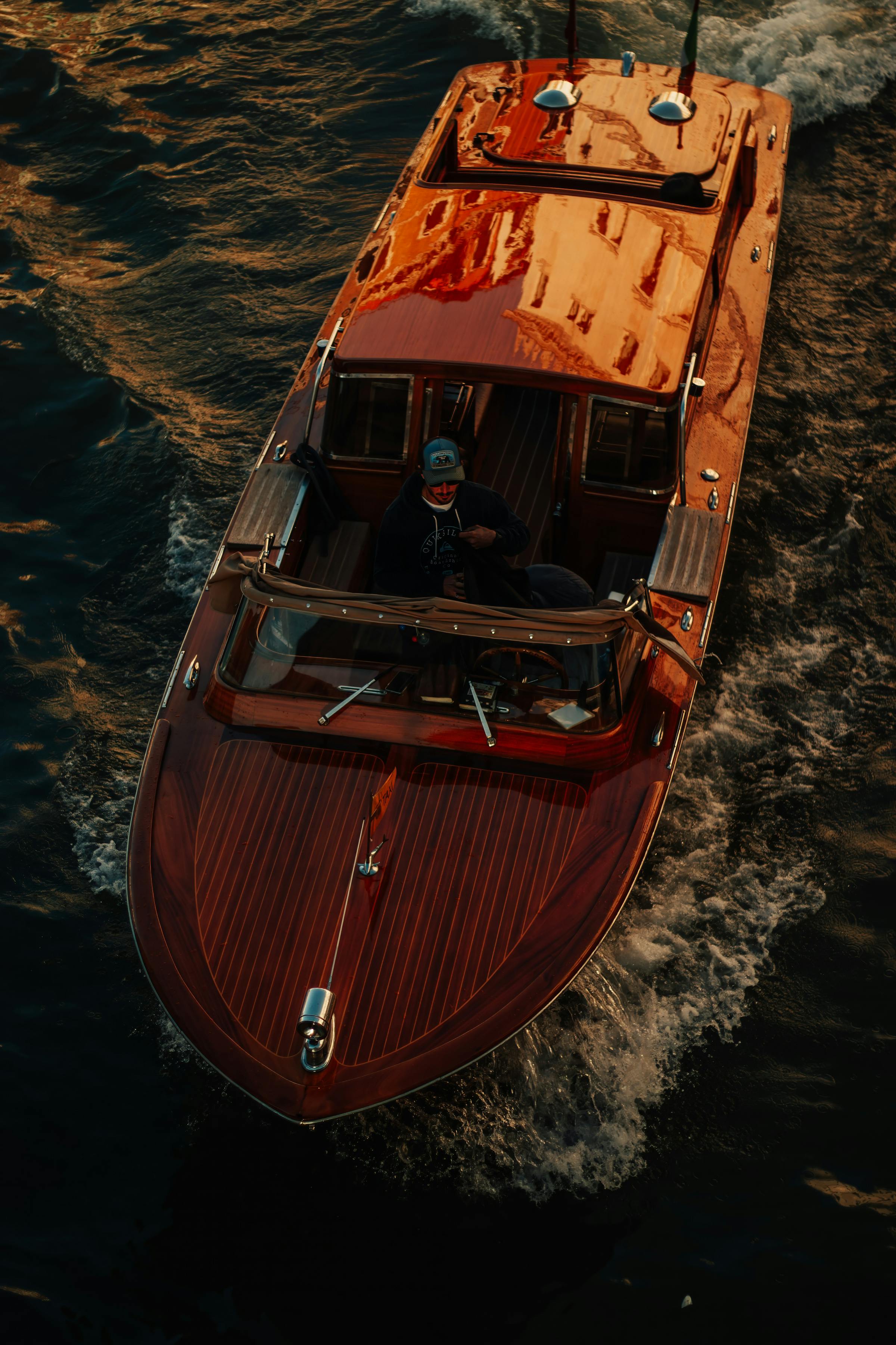 A classic varnished mahogany cruiser on the water at golden hour.