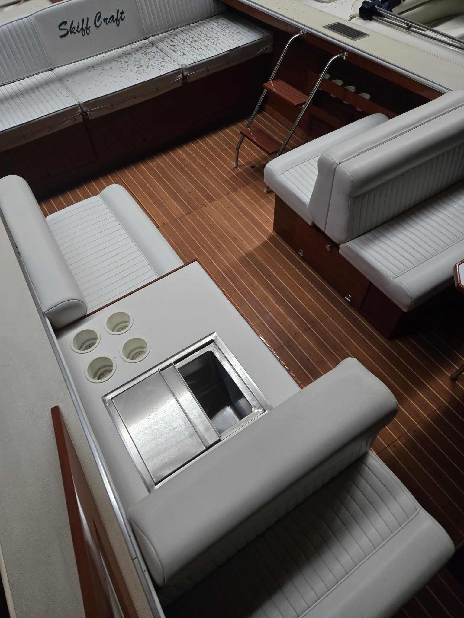 Skiff Craft teak-planked cockpit floor with white upholstered seating.