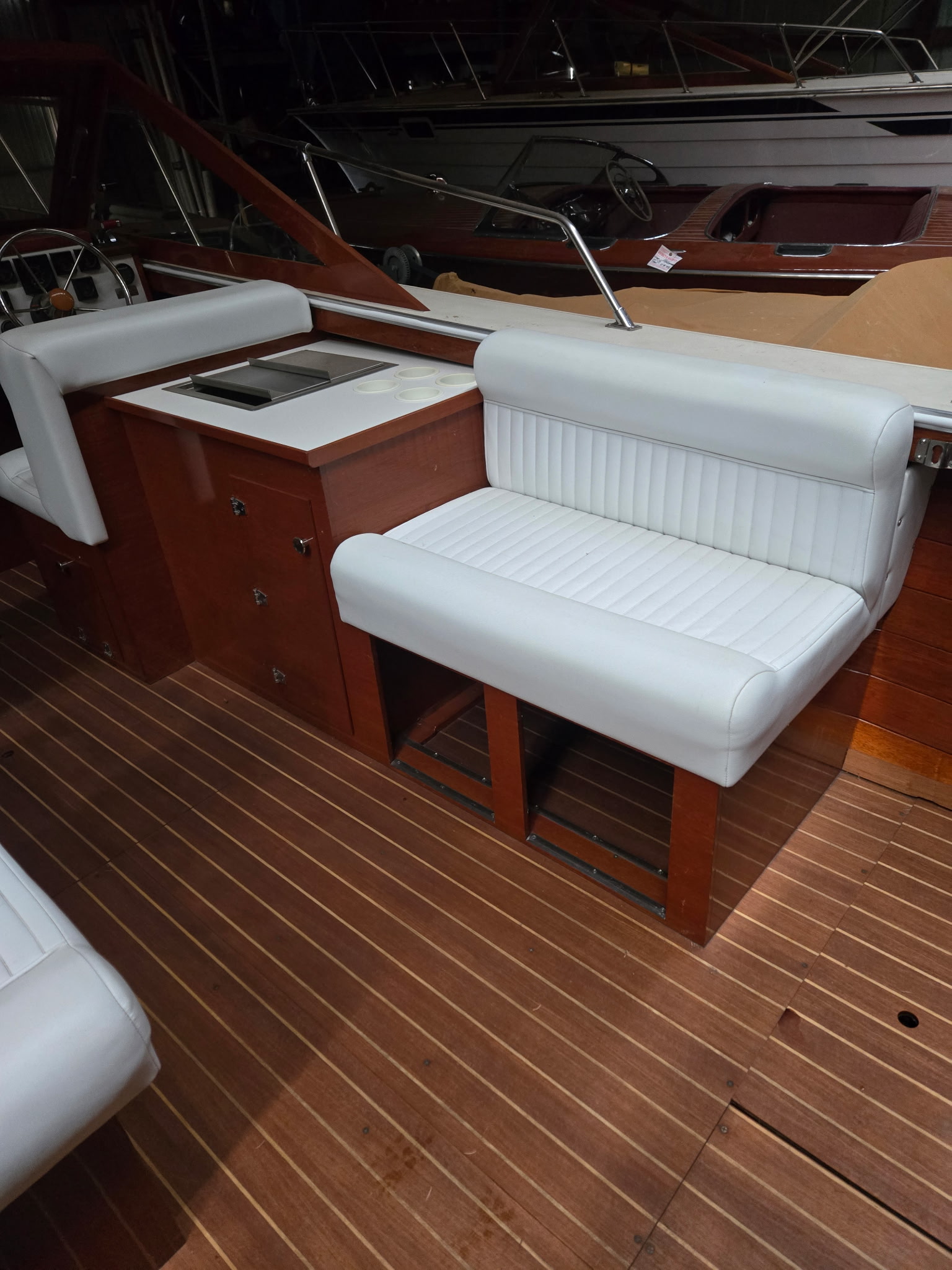 Skiff Craft interior — teak-planked cockpit floor and mahogany cabinetry, boats in background.
