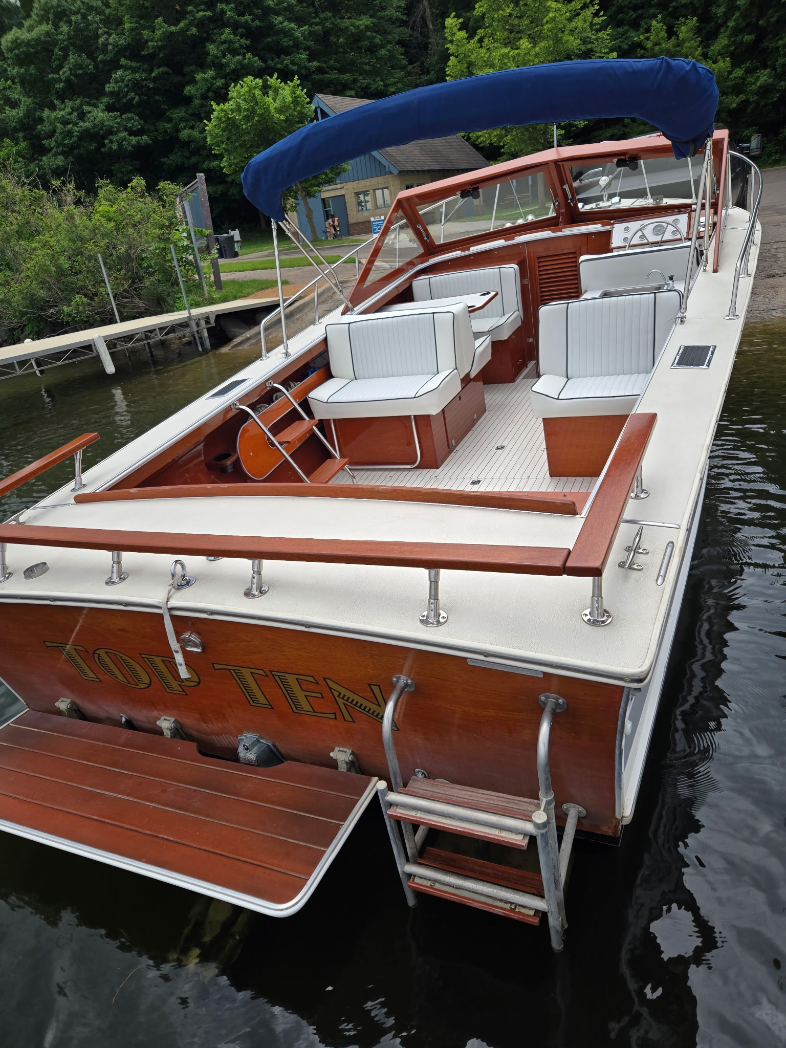 Skiff Craft stern at dock — 'Top Ten' in gold lettering, mahogany trim.